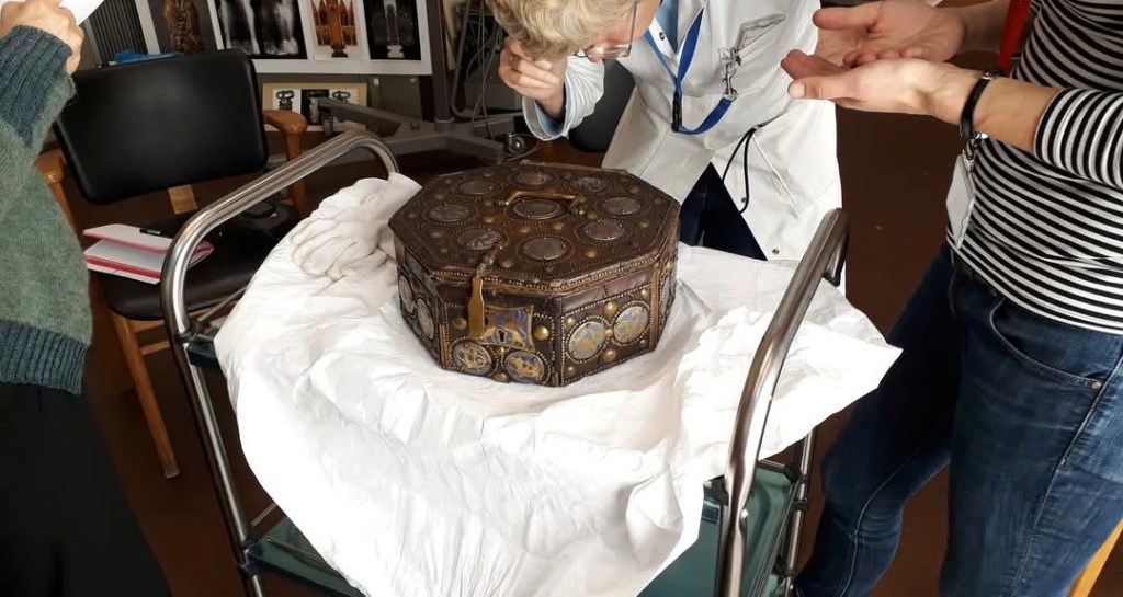 Des scientifiques sont penchés sur le coffret ils l'observent avec attention.